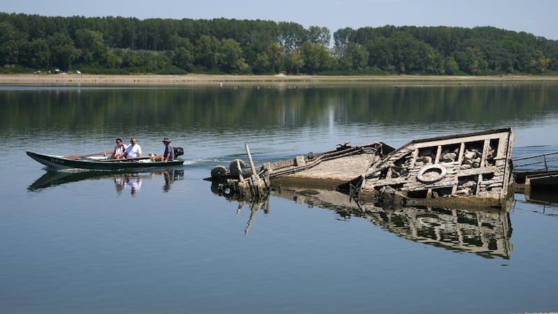 People watch the wreckage of a WWII German warship, emerged due to the drought, in front of...