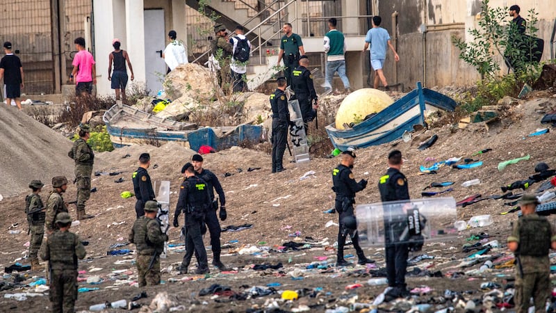 Spanish army soldiers and Guardia Civil officers stand guard as migrants return to Morocco...