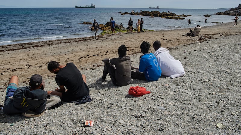 Migrants who crossed into Spain from Morocco gather on a beach in the Spanish enclave of...